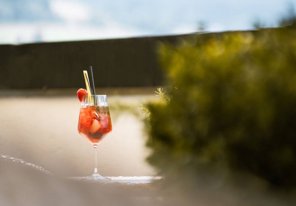 Ein Glas hausgemachter Erdbeerbowl steht auf einem Tisch auf der Außenterrasse im AllgäuSternHotel