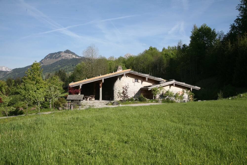 Die Sonnenkopfhütte des AllgäuSternHotels mit Almwiese und Berggipfel.